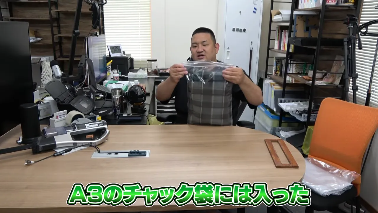 A3サイズのチャック袋に収まった圧縮された衣類を持ち上げて見せる様子