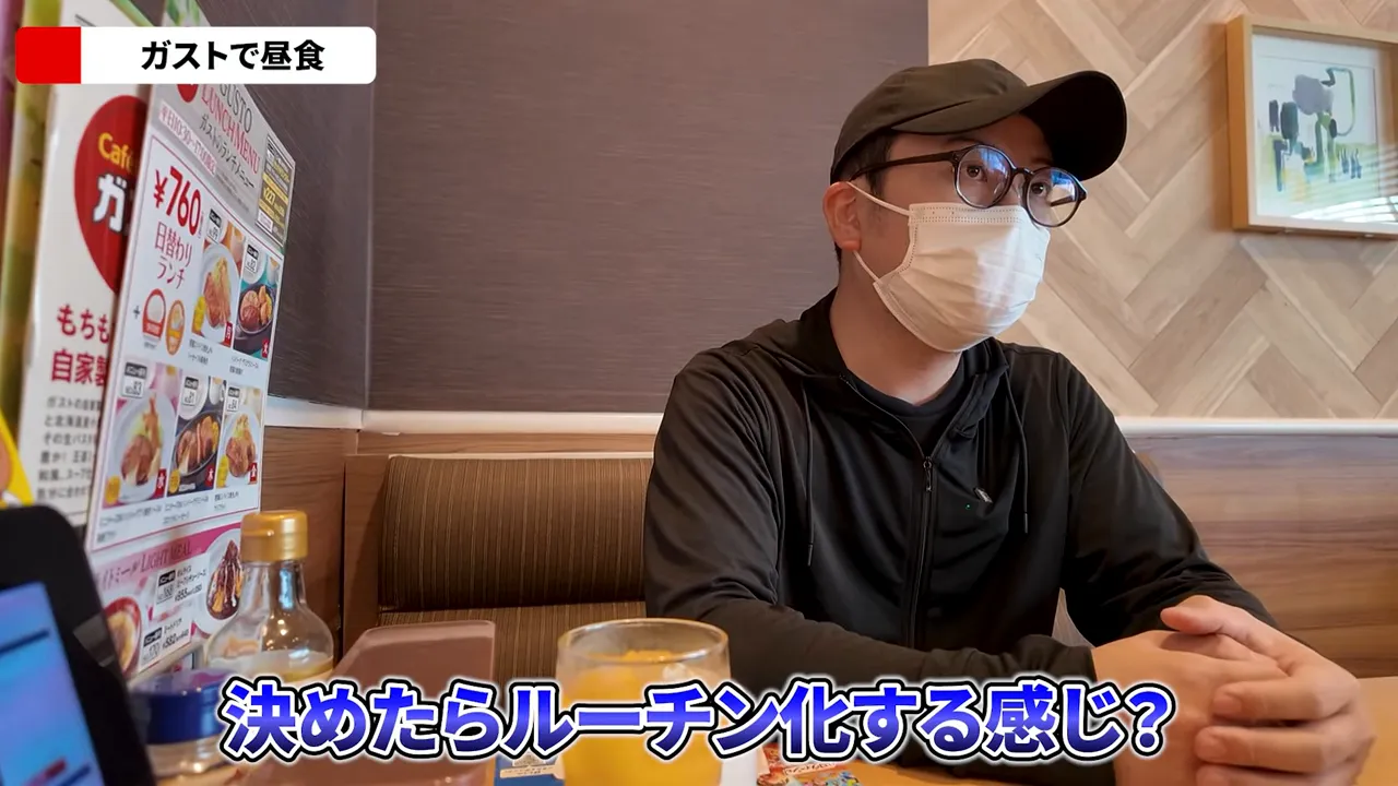 Person in cap and mask at a Gusto table with menu at left and a glass of juice visible