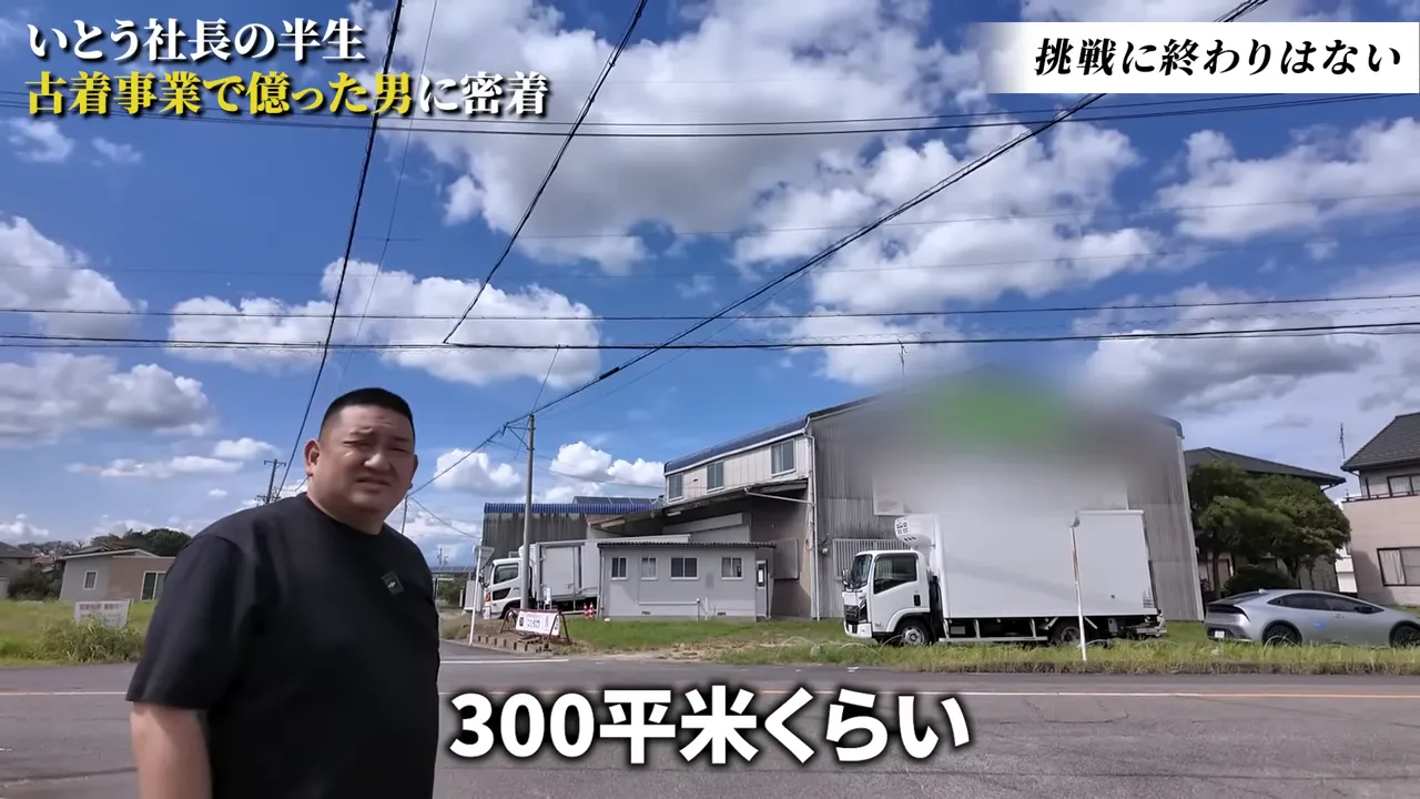 倉庫の前で説明する男性、トラックと倉庫の外観が見える