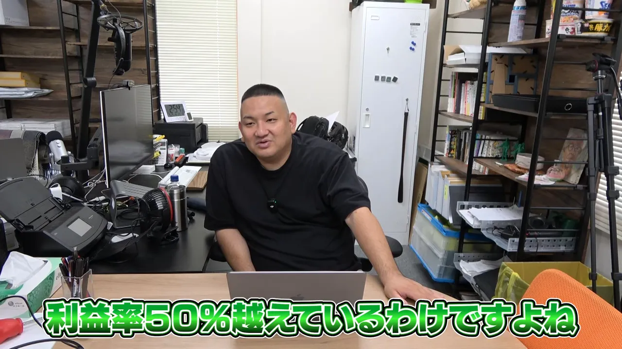 オフィスでノートPCを前に説明する人物、緑の字幕で「利益率50%越えているわけですよね」と表示された画面