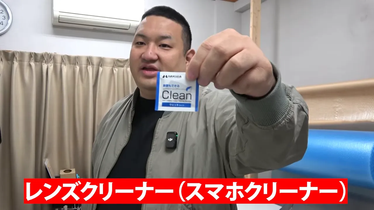スマホ用レンズクリーナーのパッケージを手に持って見せる場面