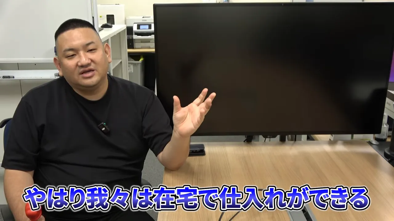 テーブルの前で話す人物と画面下に『やはり我々は在宅で仕入れができる』という字幕が出ている場面