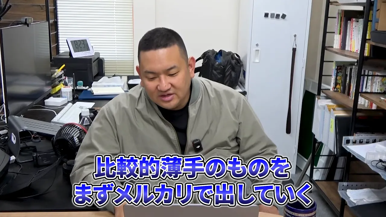 オフィスで話す男性と画面下に『比較的薄手のものをまずメルカリで出していく』と表示された鮮明なスクリーンショット
